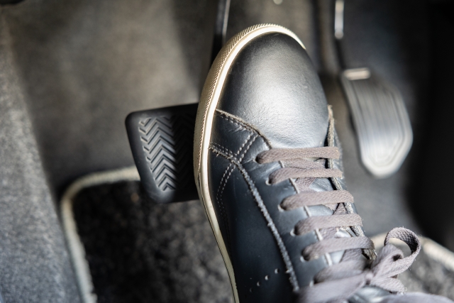 車のブレーキペダルを優しく踏み込んでいる足元の様子