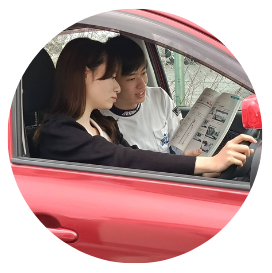 自動車ペーパードライバー講習で交通ルールの確認をしている様子。車内で教本を開き、女性の生徒さんへ優しく丁寧にサポートするタイヨウセーフティードライブ・タイヨウライディングスクール代表の志村太陽先生