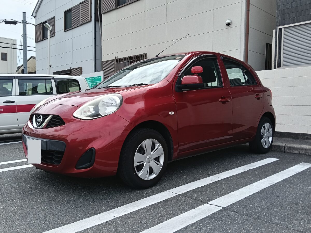 駐車場に停められたタイヨウセーフティードライブの赤い教習車。運転に不慣れなペーパードライバーでも車幅感覚がつかみやすく、駐車練習にも最適なコンパクトカー(日産マーチ)を採用しています