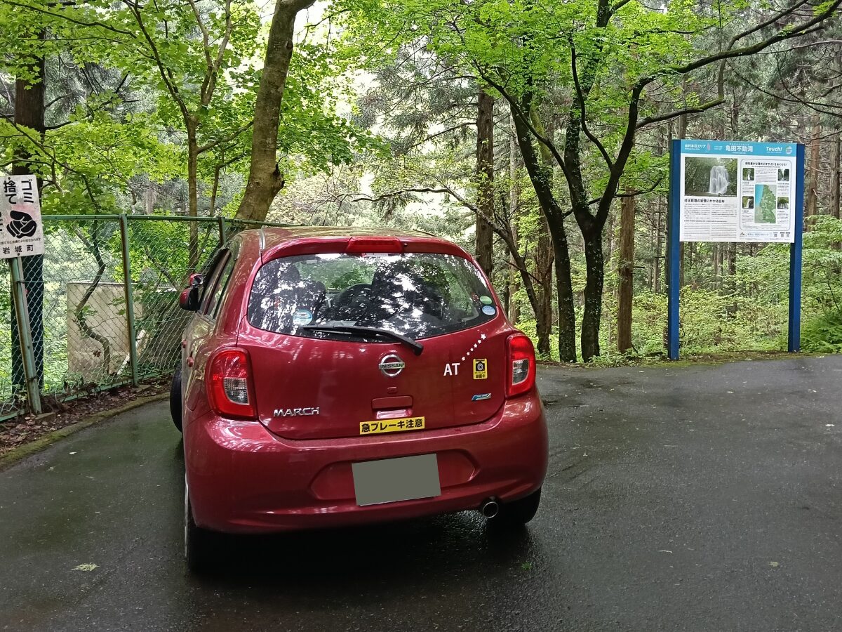 周囲の車に教習中であることを知らせるステッカーを後部に貼った、タイヨウセーフティードライブの赤い教習車。山道やカーブなど実践的なルートでのペーパードライバー講習風景