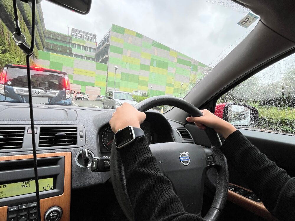 雨の日のモゾワンダーシティ周辺で渋滞の中、運転練習をするペーパードライバーの様子(出張教習ハーモニー提供)